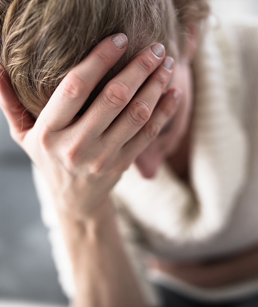 Woman with her hand on her forehead, feeling nauseous.