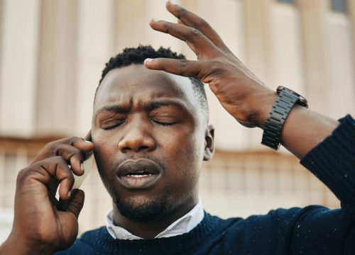Photo of a man on a cell phone dealing with a migraine
